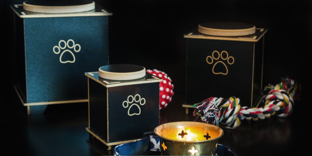 Pet cremation urns with paw print designs displayed beside a memorial candle and dog toy, symbolizing a loving and dignified tribute to a beloved pet.